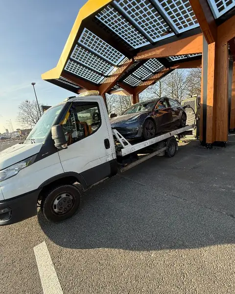 Véhicule électrique Tesla chargé sur plateau à une borne de recharge